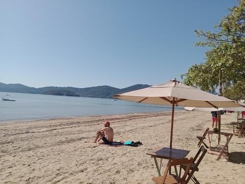 a man sitting on the beach under an umbrella at Geko Pousada Paraty in Paraty