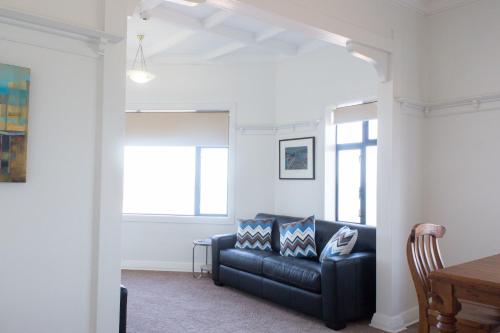 a living room with a black leather couch at The Hydro Esplanade Apartments in Dunedin