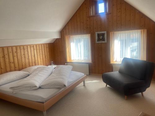 een slaapkamer met een bed en een stoel bij Casa Margerita in Flums