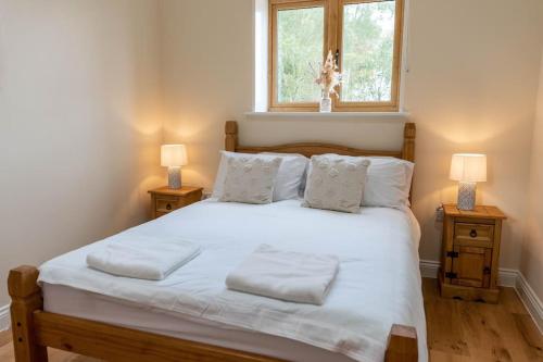 a bedroom with a large white bed with two lamps at Beautiful barn conversion surrounded by woodland near Newark Show-ground 