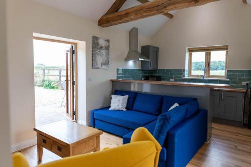 a living room with a blue couch and a kitchen at Beautiful barn conversion surrounded by woodland near Newark Show-ground 