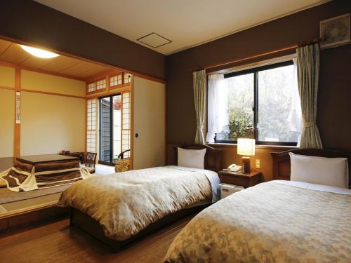 a bedroom with two beds and a window at Ryokan Kutsuroginoya Yuu in Takayama