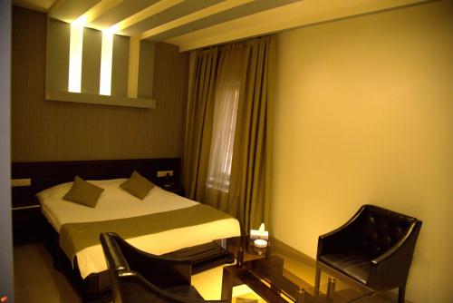 1 dormitorio con 1 cama, 2 sillas y ventana en Palma Palace Hotel, en Ereván
