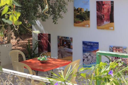 a red table with chairs and pictures on the wall at بيت الطبيعة nature house in Jerash