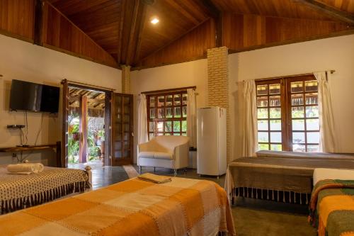 a bedroom with two beds and a tv and a chair at Pousada Capitão Gancho in Barra Grande