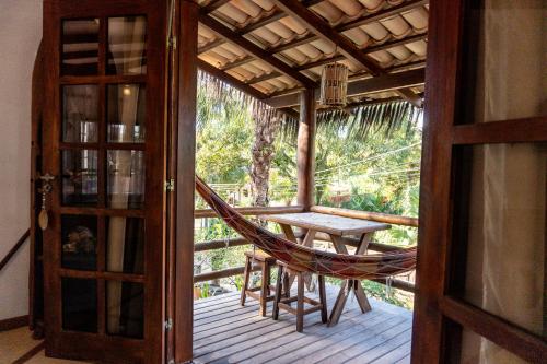 a hammock on a porch with a table and chair at Pousada Capitão Gancho in Barra Grande