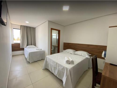 een hotelkamer met 2 bedden en een raam bij Hotel Vitória in Vitória da Conquista