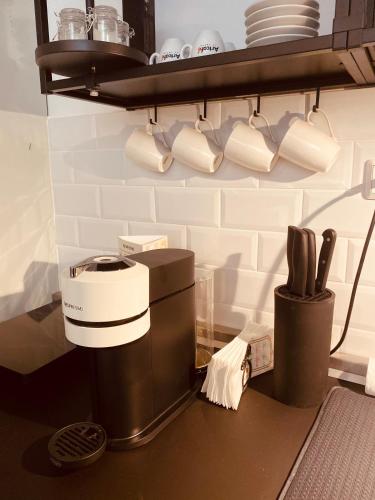 a kitchen counter with a coffee maker and cups on a shelf at Tar Pizza La Casa in Debrecen