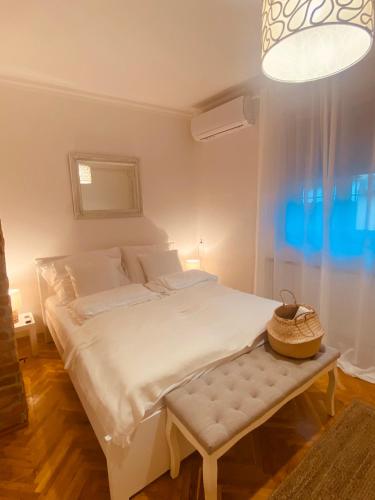 a white bed with a bench in a room at Tar Pizza La Casa in Debrecen