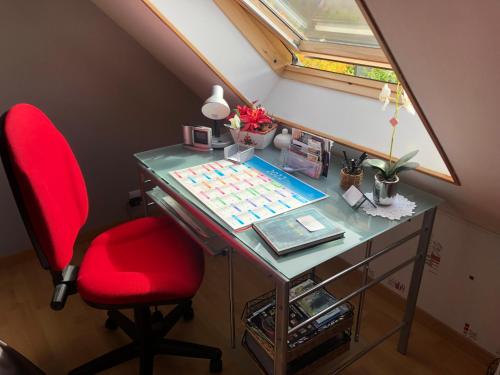 Zimmer im Dachgeschoss mit einem Schreibtisch und einem roten Stuhl in der Unterkunft Le Hameau du moulin a vent in Saint-Avertin