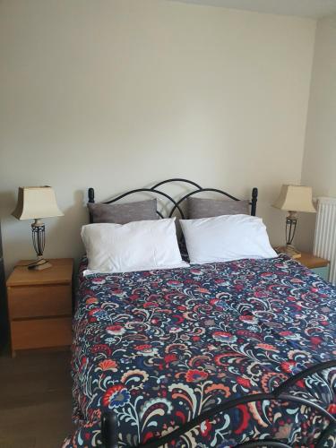 a bed with a colorful comforter and two lamps at Le Baron in Le Blanc-Mesnil