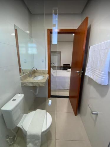 a bathroom with a toilet and a sink and a mirror at Hotel Vitória in Vitória da Conquista