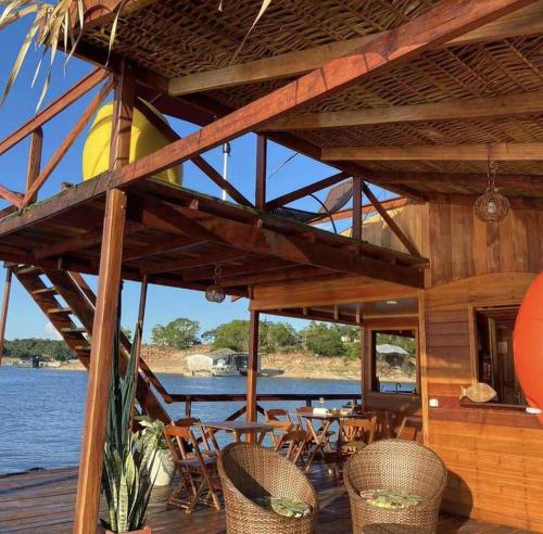 a wooden deck with tables and chairs on the water at Casa Flutuante - Experiência única in Manaus