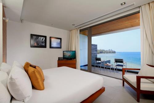 a bedroom with a bed and a view of the ocean at Cape Sienna Phuket Gourmet Hotel & Villas - SHA Extra Plus in Kamala Beach