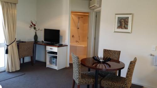 a room with a table and a television and a bathroom at Cedar Grove Motor Lodge in Nelson