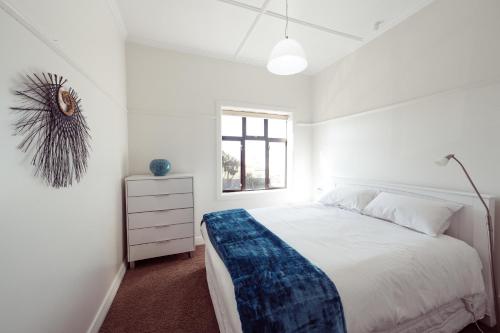a white bedroom with a large bed and a window at The Hydro Esplanade Apartments in Dunedin