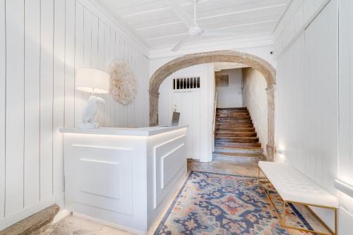 a hallway with white walls and a white table with a lamp at Chiado 44 in Lisbon