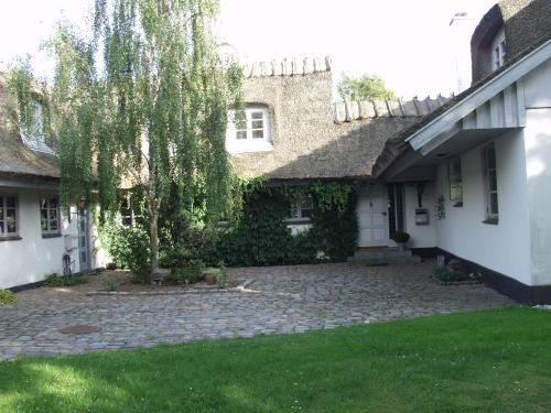 a house with a tree in front of a yard at Dyrlundgaard tilbyder charmerende ferielejlighed. in Helsinge