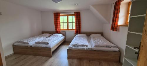 two beds in a small room with a window at Chalupa Pod Větrným Vrchem in Dolní Morava