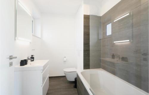 a bathroom with a tub and a toilet and a sink at Stunning Apartment In Lembruch-dmmer See With Lake View in Lembruch