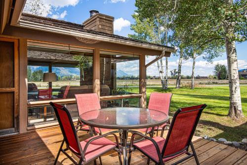 a patio with a table and chairs on a deck at Golf Creek 32 in Teton Village