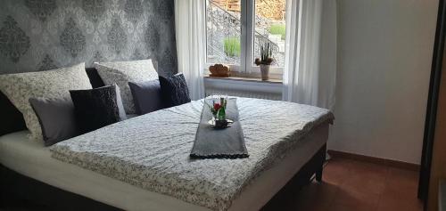 a bedroom with a bed with a table with flowers on it at Ferienwohnung MaarBurg in Ulmen