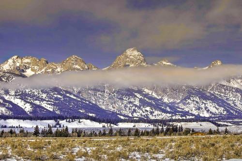 a snow covered mountain range with a cloud in front of it at Golf Creek 32 in Teton Village