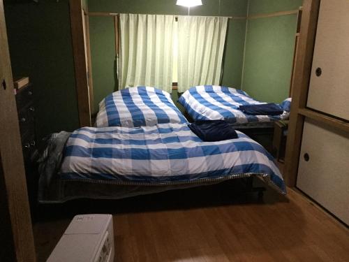 two twin beds in a room with a window at ゲストハウスやごろう in Iizuka