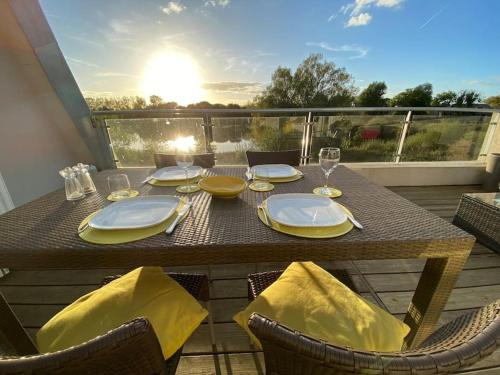 einen Tisch mit Tellern und Gläsern auf dem Balkon in der Unterkunft Reed Warbler - HM111 - Lower Mill Estate Penthouse Apartment with Spa Access in Somerford Keynes