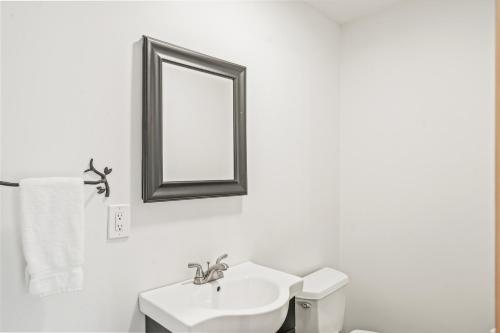 ein weißes Badezimmer mit einem Waschbecken und einem Spiegel in der Unterkunft Overlook in Warrensburg