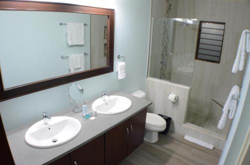 a bathroom with two sinks and a shower and a toilet at Pen Manor Modern 2 Bedroom Apartment in Boissiere Village