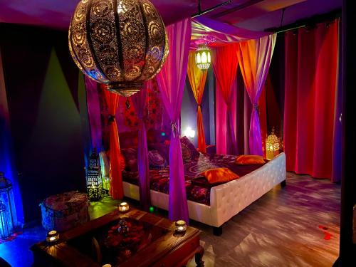 sypialnia z łóżkiem z kolorowymi zasłonami i żyrandolem w obiekcie loveroom21 w mieście Valenciennes