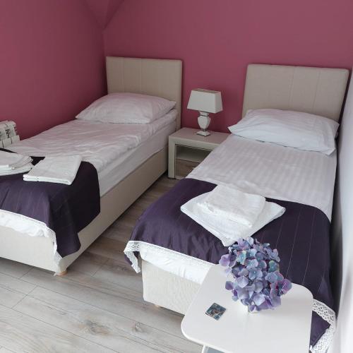 Un dormitorio con 2 camas y una mesa con flores. en Apartamenty Pod Magnolią en Białowieża