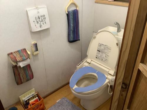 a bathroom with a toilet with a blue seat at ゲストハウスやごろう in Iizuka