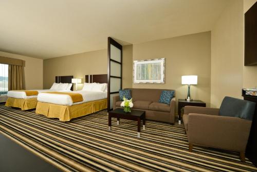 フォレストシティにあるHoliday Inn Express & Suites Forrest City, an IHG Hotelのベッドとソファ付きのホテルルーム