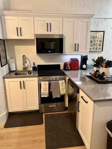 a kitchen with white cabinets and a stove and a sink at St George Resort Condo in St. George