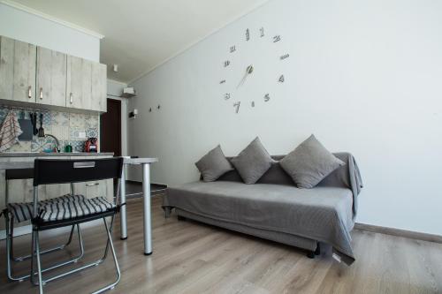 ein Wohnzimmer mit einem Sofa und einer Uhr an der Wand in der Unterkunft Modiano Studio ΙΙΙ By Socrates Junior Houses in Thessaloniki