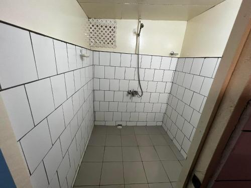 a bathroom with white tiled walls and a shower at Pension Punahaa in Nuku Hiva