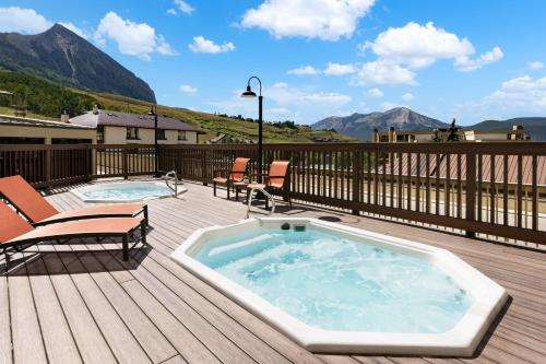 a hot tub on a deck next to two chairs at Elevation Hotel & Spa in Crested Butte