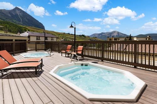 a hot tub on a deck next to two chairs at Elevation Hotel & Spa in Mount Crested Butte