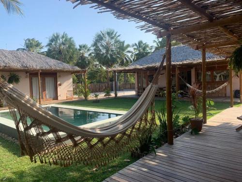 a hammock in front of a house with a pool at Casa Rosa Atins in Atins
