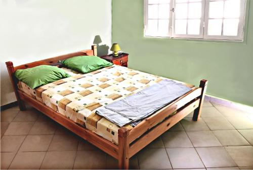 ein Holzbett in einem Zimmer mit Fenster in der Unterkunft Villa Punch Alizés 28, Route de la colline 97160 Le Moule in Le Moule