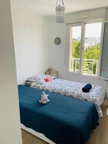 une chambre avec un lit avec un animal en peluche dessus dans l'établissement Appartement familial, 2 ch., balcon + parking, à Trouville-sur-Mer