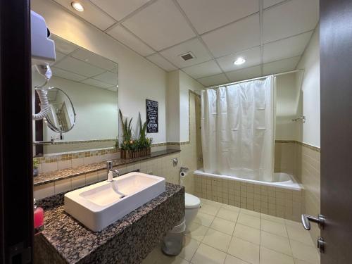 een badkamer met een wastafel, een toilet en een spiegel bij Route 66 Beach Hostel in Dubai