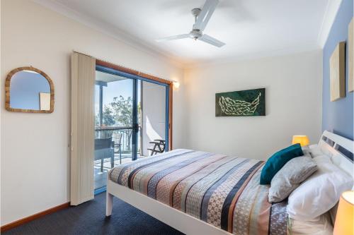 a bedroom with a bed and a balcony at Baggies On Dutchies, 9 Burbong Street - Large Pet Friendly house with spectacular waterviews, Wi-Fi and air con in Nelson Bay