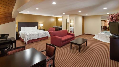 a hotel room with a bed and a living room at Best Western Jacksonville Inn in Jacksonville