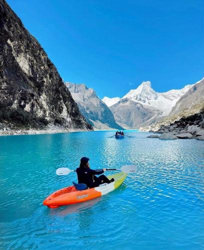 a person in an orange kayak on a lake with mountains at Hospedaje apus in Huaraz
