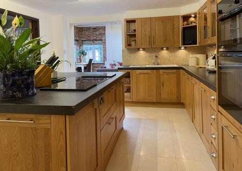 a kitchen with wooden cabinets and a black counter top at The Coach House by Bloom Stays in Harrietsham