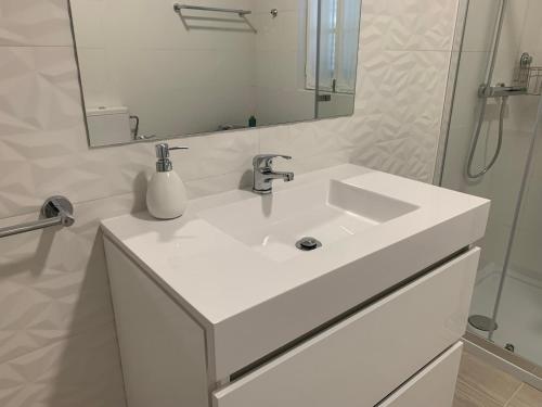 La salle de bains blanche est pourvue d'un lavabo et d'un miroir. dans l'établissement Torreira Vacation Homes - Sea House, à Torreira