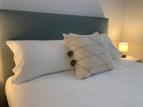 - un lit blanc avec des oreillers blancs et une tête de lit bleue dans l'établissement Torreira Vacation Homes - Sea House, à Torreira